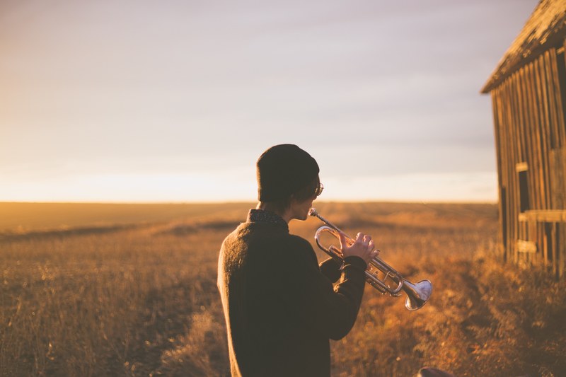 musician playing trumpet alone in an empty forest field, trumpet player 4k