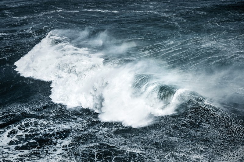 a large wave curling and foaming white in the deep blue ocean at nazar, white foaming wave in the deep blue 4k