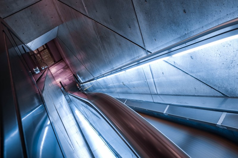 looking down at an urban escalator enclosed in a concrete tunnel at omotesando hills, escalator in omotesando hills 4k
