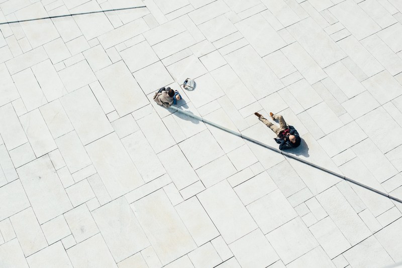 a drone shot of a man photographing a woman with a toddler in an empty plaza, family in a plaza from above 4k