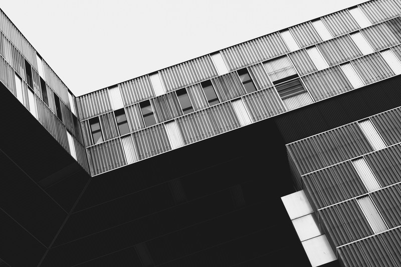 a black and white shot of an industrial style building in vienna, the people who must work there 4k