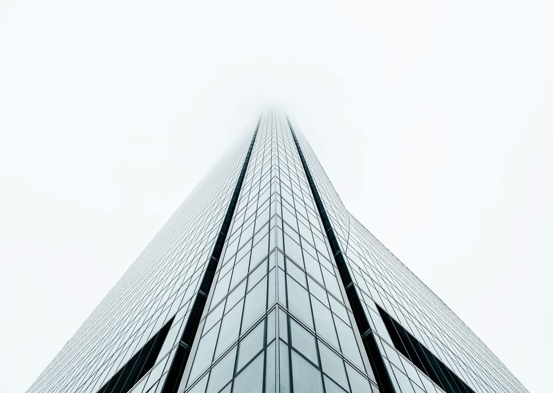 fog covers the top of a tall building with rectangular glass design facade in madrid, _into the fog 4k