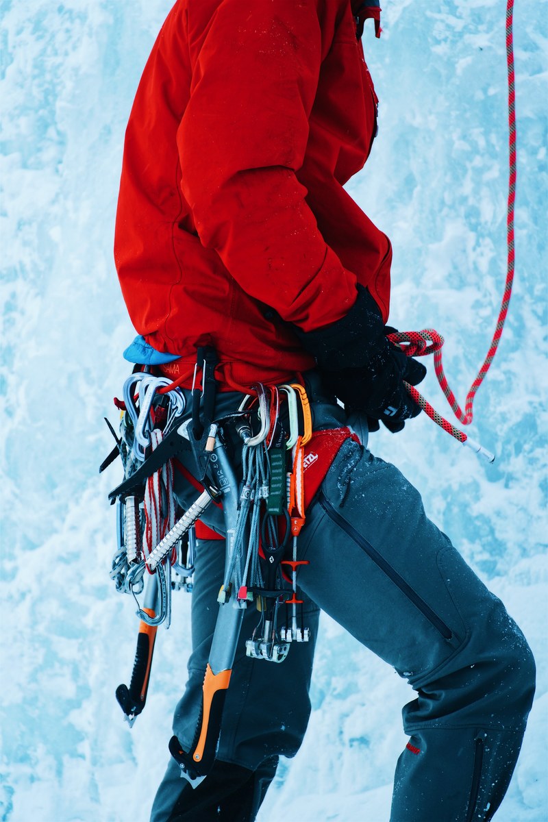 a person with ice climbing gear strapped to a harness on an ice wall, mountain climber at bridal veil falls 4k