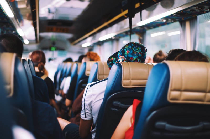 a back to front shot of a bus full of people in blue and tan seats, people in bus seats 4k
