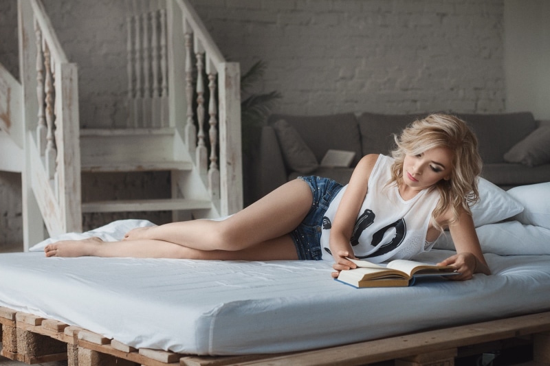 in bed, barefoot, curly hair, 1080P, s, legs, leisure activity, women indoors, reading, top, indoors, model, books, black, hair, sitting, tank top, bed
