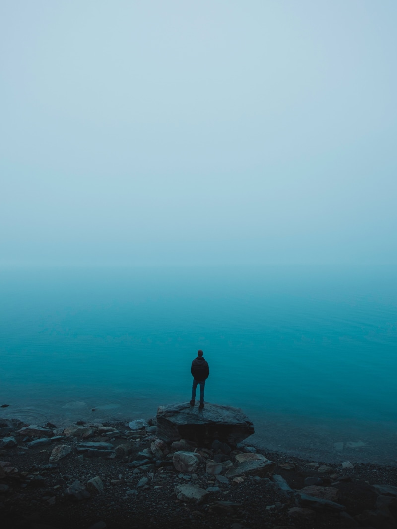beauty in nature, hiking, nature, backpack, man, blue, loneliness, stones, cliff, sky, sunset, solid, water, women, scenics - nature, alone, landscape