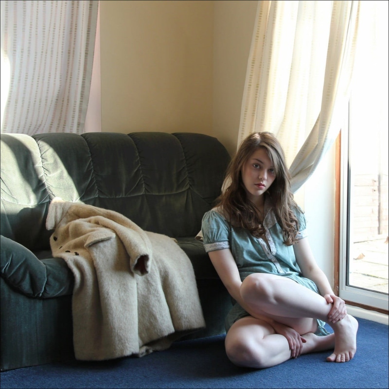 long hair, barefoot, on the floor, curtain, adult, 720P, domestic room, day, lifestyles, living room, contemplation, window, casual clothing, one person