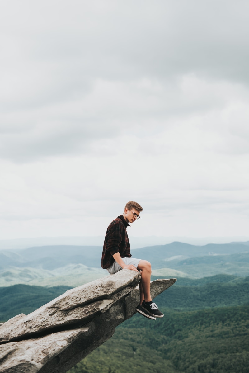 full length, one person, cloud - sky, stone, sky, autumn, perched, sitting, cliff, tranquility, edge, scenics - nature, casual clothing, day, nature, mountain range