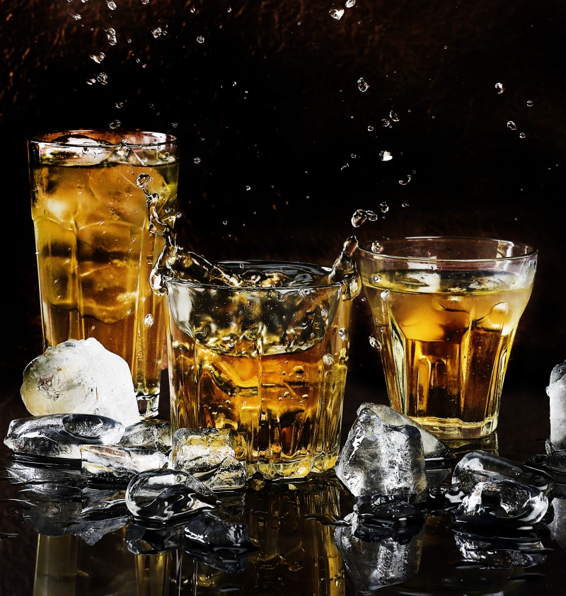 glass, transparent, household equipment, ice, reflections, liquor, black background, liquid, whisky, splash, table, alcohol, cubes, refreshment, no people