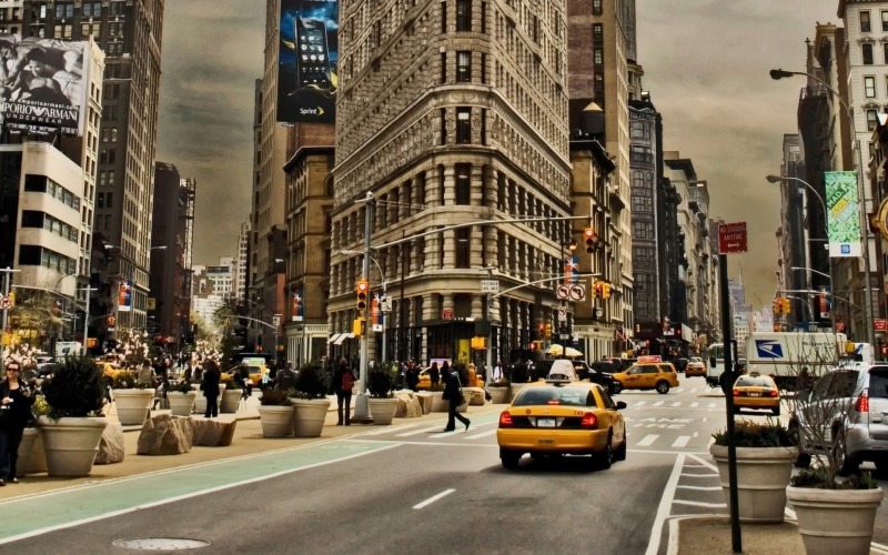 transportation, land vehicle, travel, Flatiron Building , outdoors, traffic lights, Manhattan, day, city street, New York City, street, billboards, incidental people