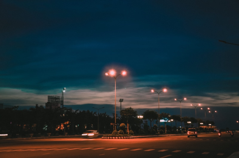road, lampposts, building exterior, transportation, motor vehicle, evening, highway, built structure, outdoors, blue sky, building, car, land vehicle, cars