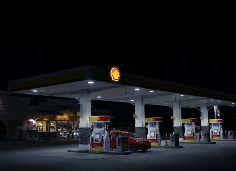 vehicle, building exterior, human, automobile, parked, copy space, gas station, sky, fuel pump, machine, red, urban, pump, petrol, architecture, fuel and power generation