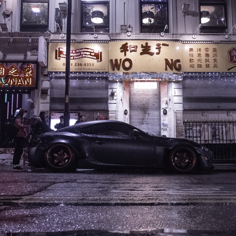 building exterior, town, western script, mode of transportation, road, outdoors, automobile, person, luxury, human, toyota, parking, land vehicle, car