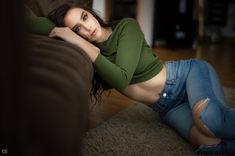 looking at viewer, Anna Bous, crop top, brown eyes, portrait, 4K, on the floor, model, women indoors, belly, brunette, jeans, green top, lying on side