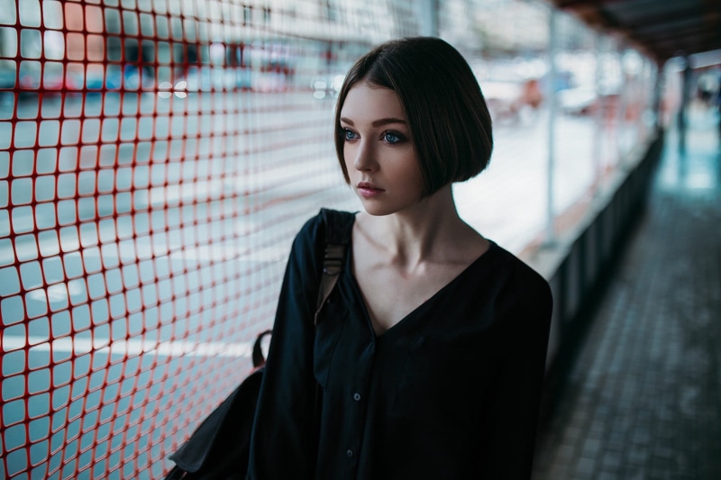v, one person, button, waist up, sleeved, headshot, neck, black, short hair, portrait, blue eyes, beautiful woman, contemplation, urban, women, face, young women
