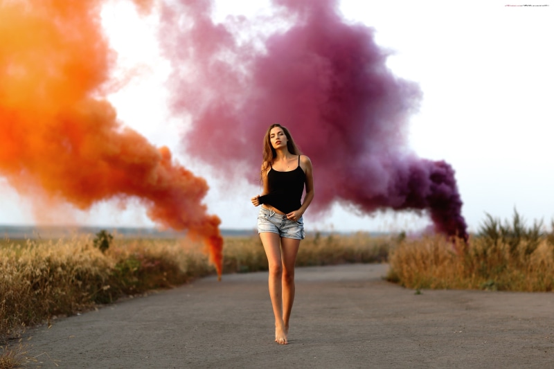 smoke - physical structure, colored smoke, standing, black, outdoors, jean shorts, lifestyles, full length, shorts, road, young women, black tops, long hair