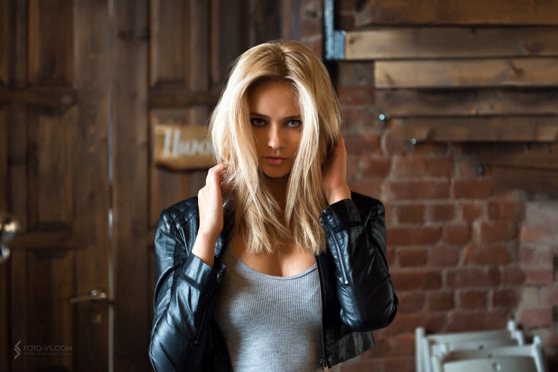 touching hair, grey tops, women indoors, leather jackets, women, 1080P, portrait, blue eyes, tanned, black jackets, long hair, blonde