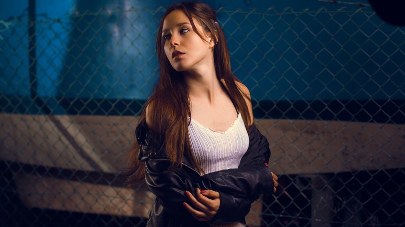 long hair, model, one person, leather jackets, real people, tank top, red nails, lifestyles, boundary, hairstyle, chainlink fence, looking, women outdoors