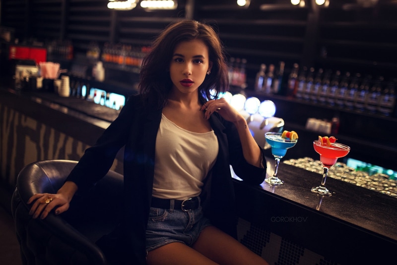 martini, drinking, looking at camera, cardigan, sitting, food and drink, hairstyle, s, alcohol, one person, portrait, brunette, fashion, beauty, glass