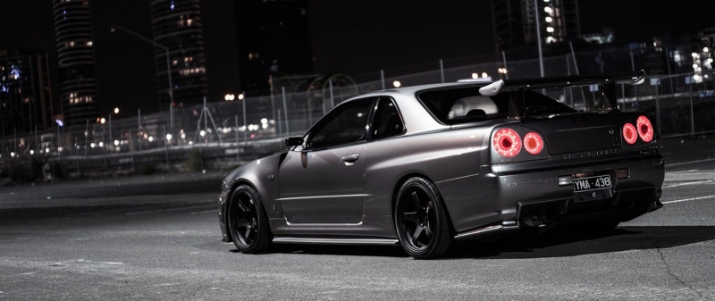 Nissan Skyline GT-R, building exterior, 2K, gray, car, architecture, on the move, road, land vehicle, outdoors, transportation, mode of transportation