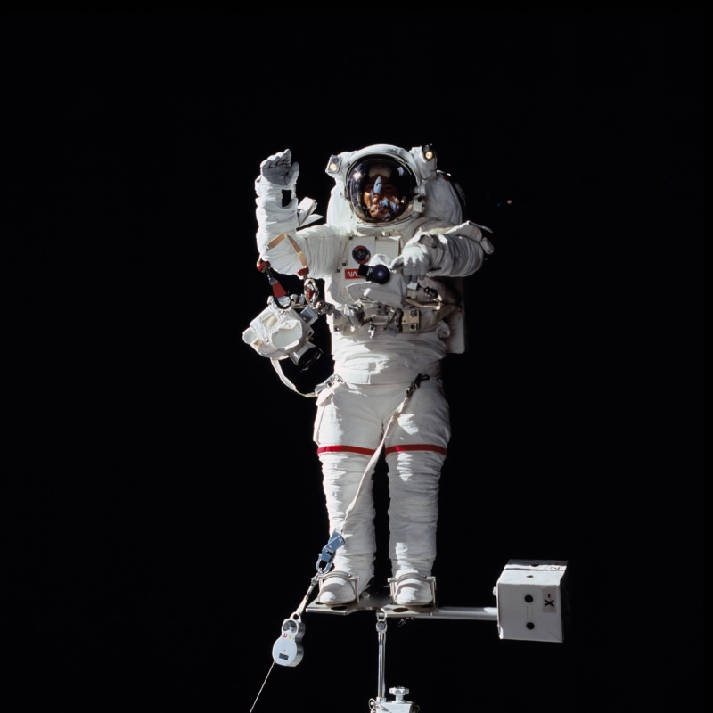 spacewalk, excitement, pack, suit, studio shot, headwear, extravehicular activity, standing, astronaut, black background, looking at camera, exploration