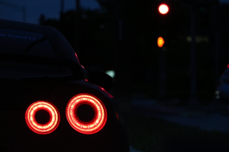 dark, vehicle light, motor vehicle, focus on foreground, night, taillight, no people, red, traffic, communication, road, mode of transportation, transportation