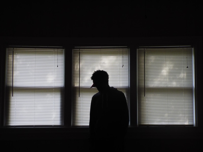 black Color, loneliness, real people, room, dark, front, window blinds, depression - sadness, shutter, silhouette, looking, person, adult, one Person, lifestyles