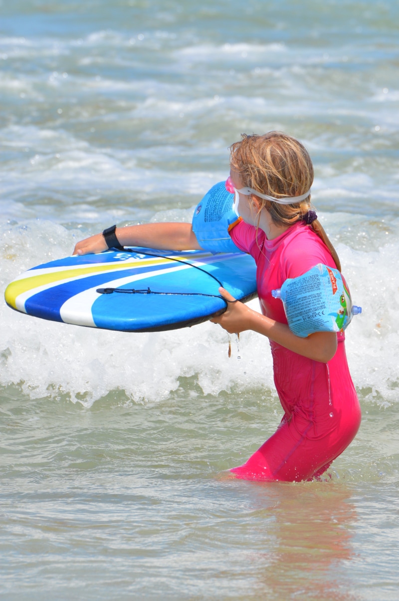 lifestyles, motion, uv-resistant clothing, innocence, beach, sea, waves, child, outdoors, holding, real people, holiday, swimming goggles, surf, people
