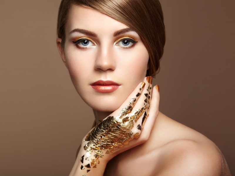 simple background, human body part, painted nails, women, 1080P, gold, looking at camera, headshot, wealth, luxury, human face, indoors, glamour, bare shoulders