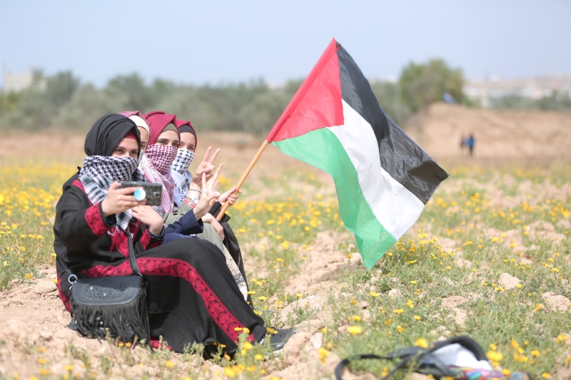 people, lifestyles, strip, togetherness, sitting, women, men, palestine, young men, day, two people, leisure activity, young adult, flag, nature, adult