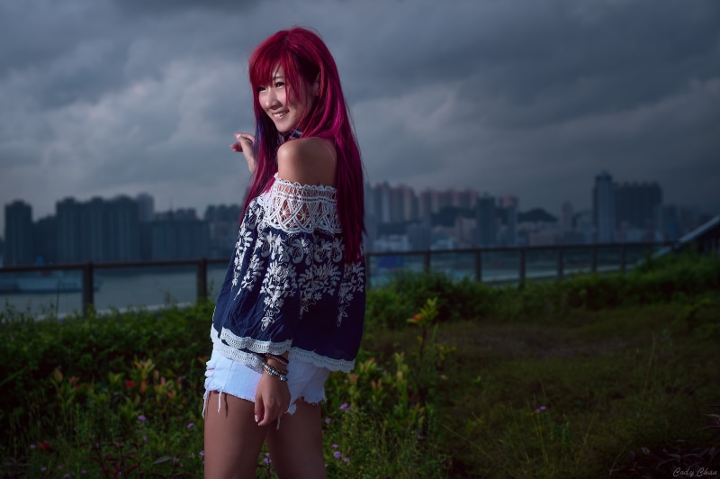 smiling, sky, jean shorts, long hair, lifestyles, young women, blue tops, beautiful woman, one person, 4K, built structure, fashion, cloud - sky, standing