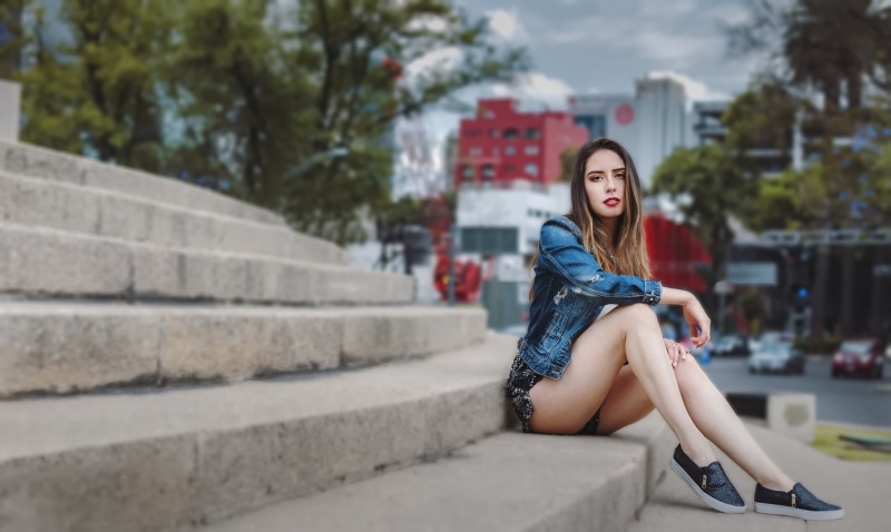 sitting, young adult, long hair, leisure activity, beautiful woman, denim, brunette, jean shorts, outdoors, steps and staircases, lifestyles, portrait