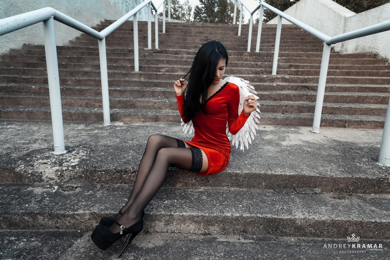 red dress, skinny, young adult, one person, v, neck, 2K, beautiful woman, full length, sitting, real people, high heels, lifestyles, mini, outdoors, women