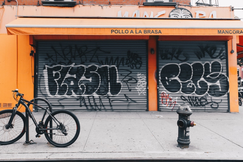 bicycle, graffiti, street art, outdoors, land vehicle, fire hydrant, near, hydrant, mode of transportation, fire, footpath, urban, building exterior, the big apple