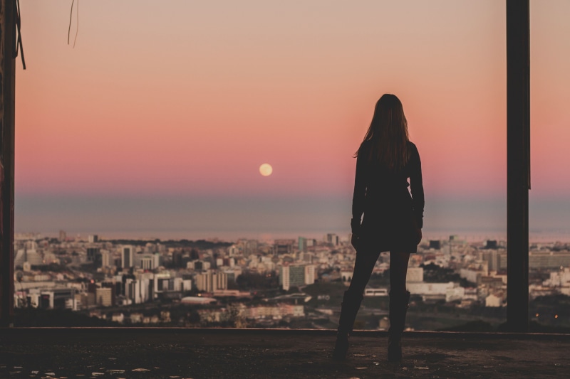 standing, real people, architecture, view, woman, people, sad, rear view, full length, tower, adult, hour, leisure activity, sunset, building, skyline
