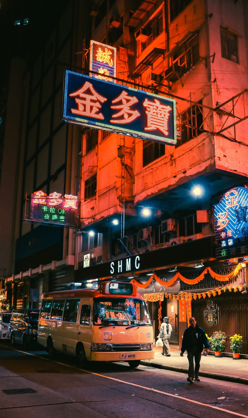 evening, motor vehicle, asia, car, transport, building, building exterior, near, bus, night, pedestrian, cyberpunk, real people, road, outdoors, text, neon