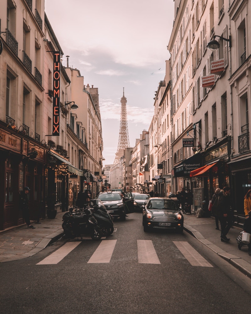 incidental people, cars, paris, office building exterior, street, eiffel tower, travelling, city, road, outdoors, land vehicle, building exterior, motor vehicle