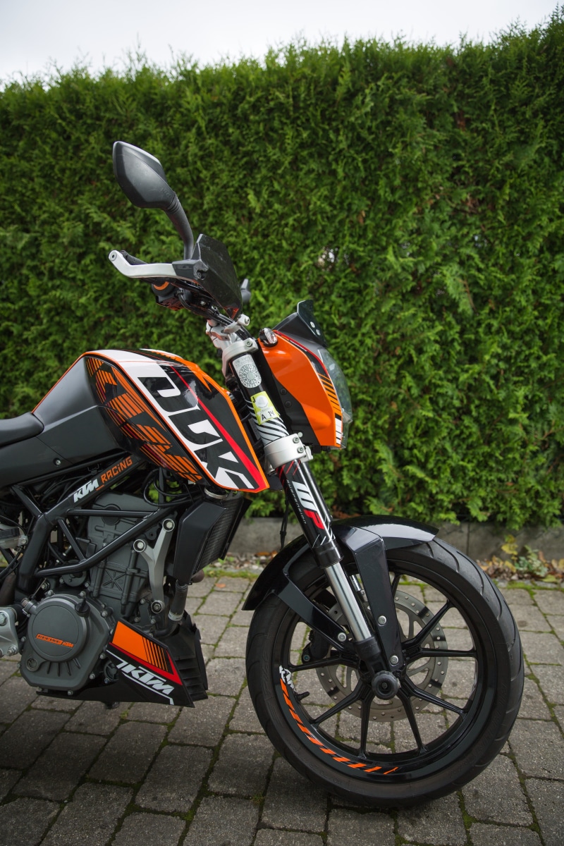 tree, day, land vehicle, mode of transportation, duke, motorcycle, plant, road, outdoors, parking, no people, sport, 125cc, wheel, footpath, transportation