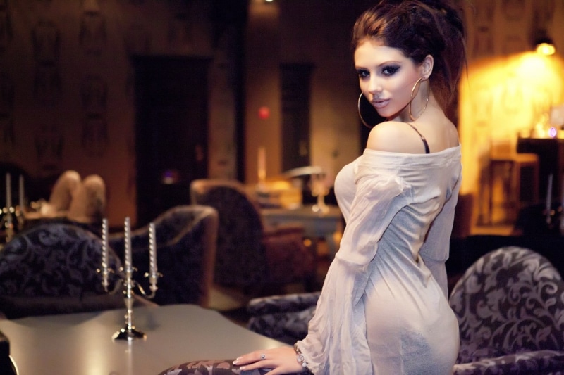one person, clothing, table, white dress, hairstyle, hoop earrings, brunette, gray, model, woman, near, wearing, makeup, standing, elegance, looking back