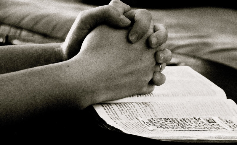 focus on foreground, christianity, adult, furniture, people, activity, religious, hand, bible, human foot, prayer, jesus, relaxation, faith, leisure activity