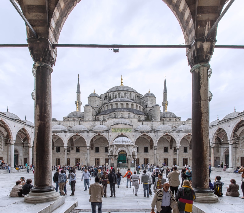 building exterior, blue, beside, sky, large group of people, arch, islam, person, building, religion, travel destinations, outdoors, architectural column