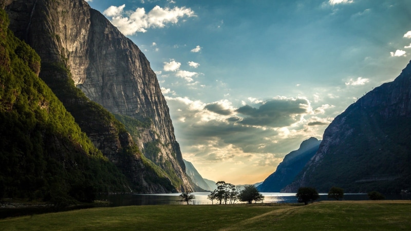 sky, sun rays, non-urban scene, grass, architecture, water, plant, rock, trees, landscape, cloud - sky, lake, tranquility, scenics - nature, solid, island