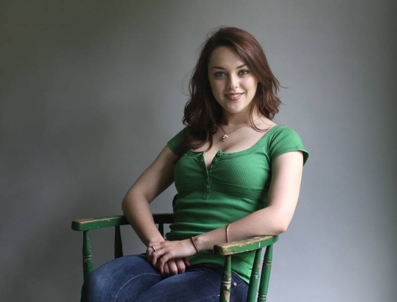 seat, chair, front view, smiling, adult, sitting, young women, Imogen Dyer, indoors, 720P, young adult, gray background, s, three quarter length, casual clothing