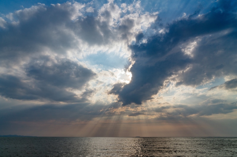 water, stormy, sun, ocean, sunlight, beauty in nature, paradise, scenics, beach, outdoors, seascape, tourism, sunny, sunbeam, nature, darkness, urban skyline