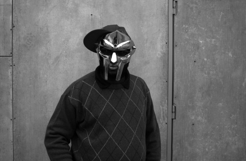 front view, mask, hip hop, leisure activity, MF DOOM, obscured face, architecture, casual clothing, real people, mask - disguise, wall - building feature