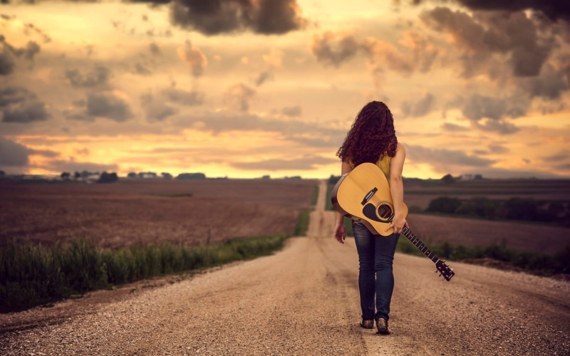 lifestyles, one person, women, jeans, string instrument, curly hair, land, real people, women outdoors, dreadnought, guitar, brown, sunset, field, Nebraska