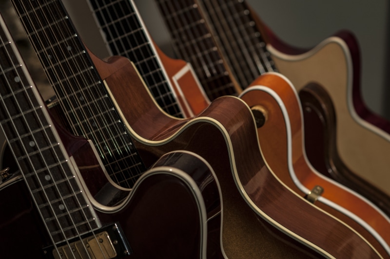 string, fret, brown, indoors, wood - material, song, music, order, black background, studio shot, guitars, bowed stringed instrument, in a row, musical equipment