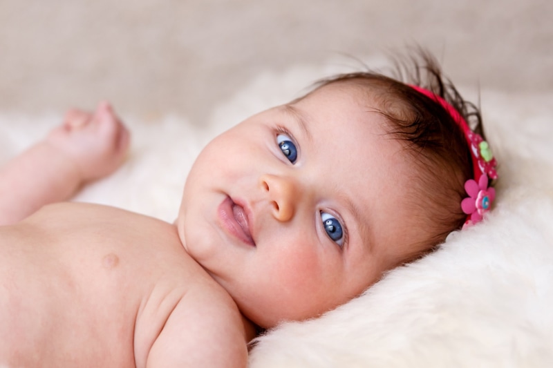 bed, happiness, small, smiling, hairband, flowers in her hair, lying on back, looking at camera, lying, human Face, child, beginnings, young, new born