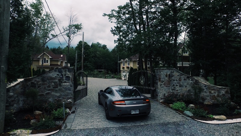film, city, building exterior, money, aston martin, road, architecture, day, built structure, drone, sky, lake memphremagog, no people, car, residential district
