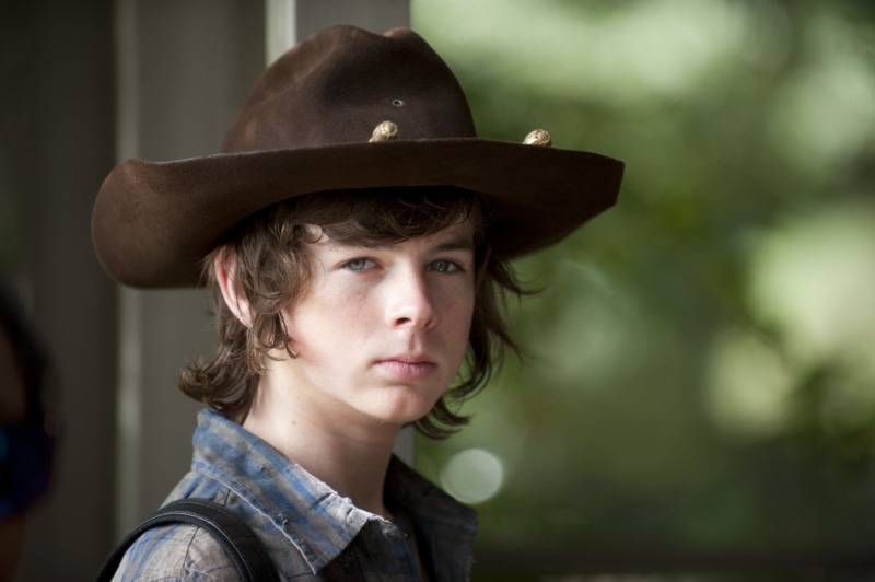 hairstyle, focus on foreground, looking away, TV Show, lifestyles, casual clothing, clothing, hat, one person, looking, young adult, The Walking Dead, Chandler Riggs